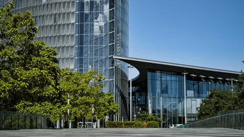 Modern glass building with trees and blue sky.