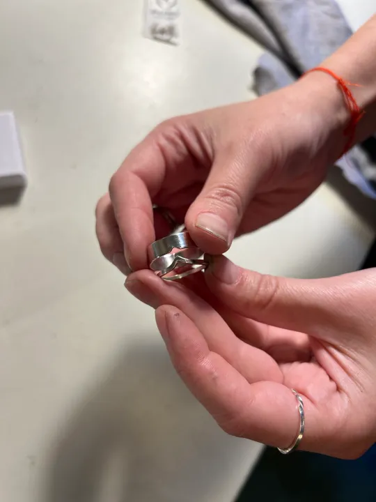 Hands holding a silver ring indoors.
