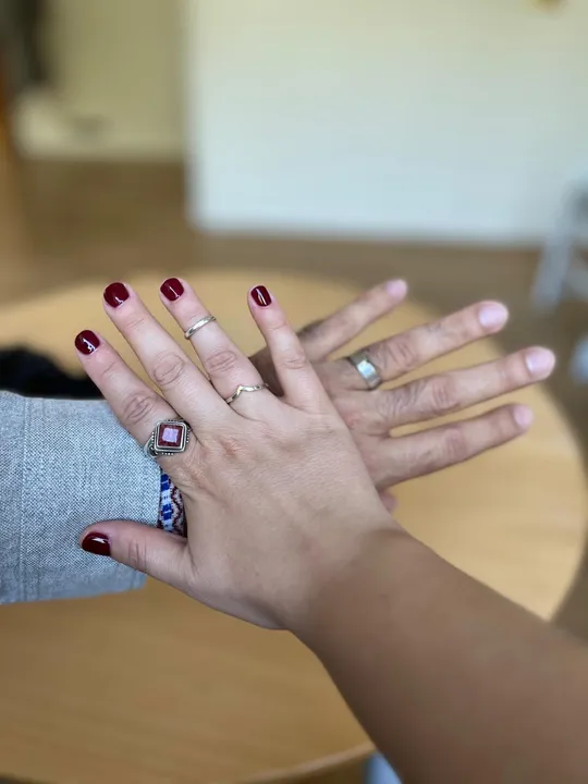 Hands with rings crossing on table.