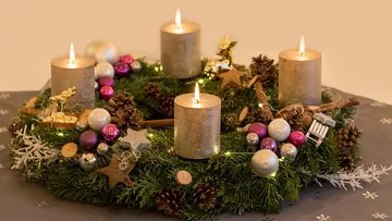 Christmas wreath with lit candles on table.